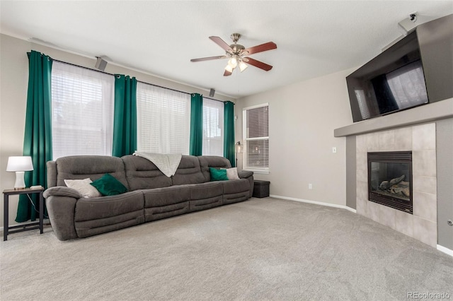 living area featuring baseboards, a ceiling fan, carpet flooring, and a tiled fireplace