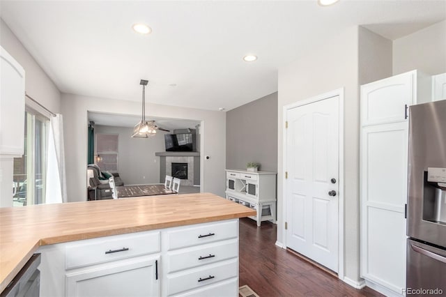 kitchen featuring appliances with stainless steel finishes, white cabinets, a fireplace, wooden counters, and dark wood-style flooring