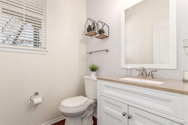 bathroom featuring vanity, toilet, and baseboards