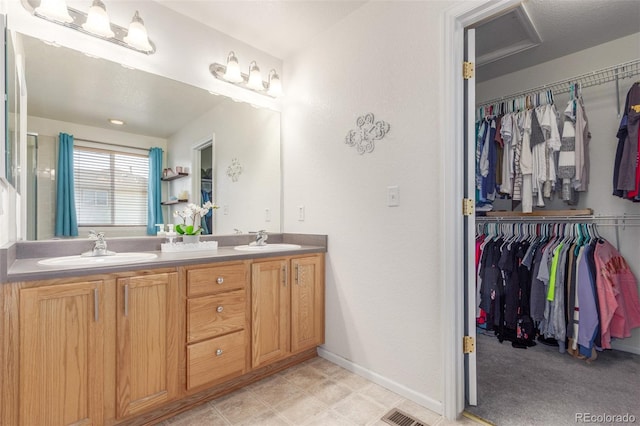 full bathroom featuring double vanity, a spacious closet, and a sink