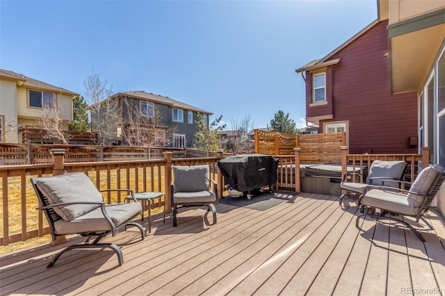 wooden deck with area for grilling, fence, and a hot tub