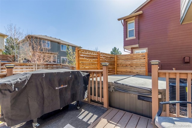 wooden deck featuring cooling unit, area for grilling, and a hot tub