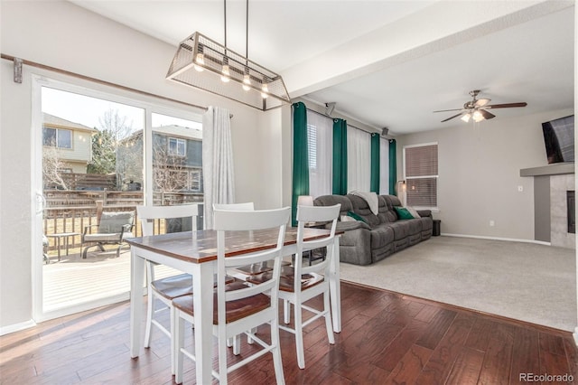 dining space featuring a wealth of natural light, beamed ceiling, wood finished floors, and a fireplace