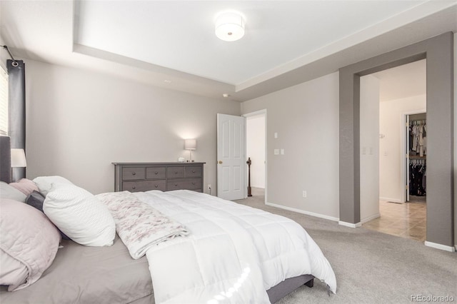 bedroom with a raised ceiling, baseboards, and light carpet