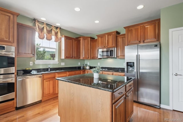 5603 Van Bibber Ct, Golden, CO 80403 - kitchen with stainless steel appliances, light wood finished floors, a kitchen island, dark stone counters, and recessed lighting