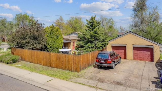 view of front of house with fence, a garage, and stucco siding