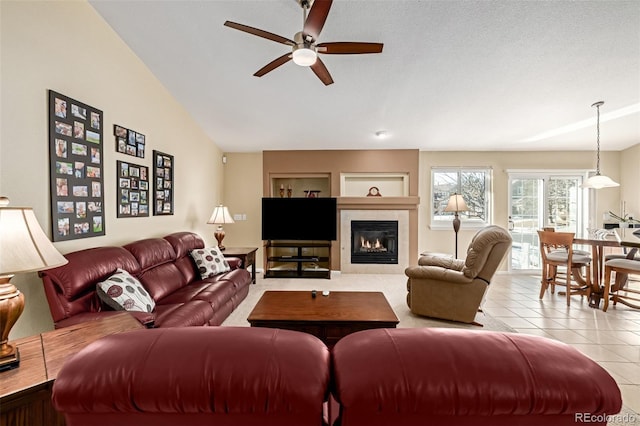 living room featuring ceiling fan, light tile patterned flooring, a fireplace, a textured ceiling, and built in shelves