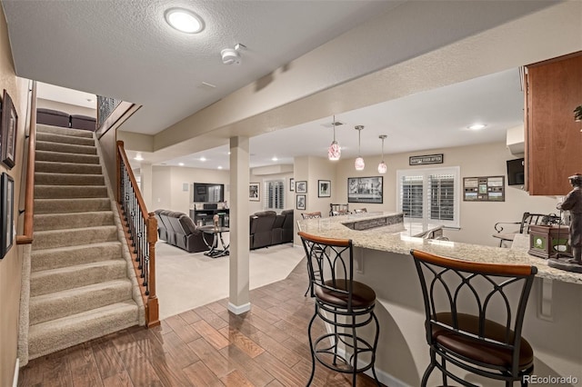 kitchen with kitchen peninsula, a kitchen breakfast bar, light stone counters, and pendant lighting