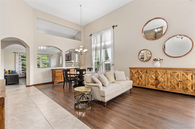 1831 Ashford Cir, Longmont, CO 80504 - living room with arched walkways, wood finished floors, healthy amount of natural light, a towering ceiling, and a chandelier
