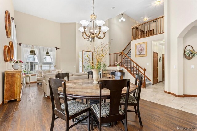 1831 Ashford Cir, Longmont, CO 80504 - dining room featuring a high ceiling, stairway, arched walkways, wood-type flooring, and a chandelier
