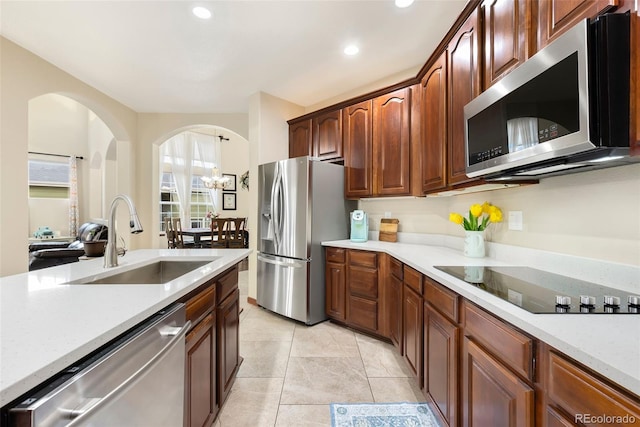 1831 Ashford Cir, Longmont, CO 80504 - kitchen with stainless steel appliances, a sink, light countertops, arched walkways, and recessed lighting