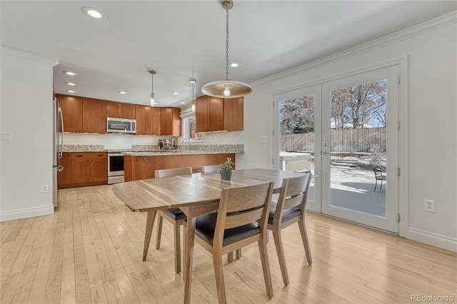 dining area featuring french doors, crown molding, and light hardwood / wood-style flooring