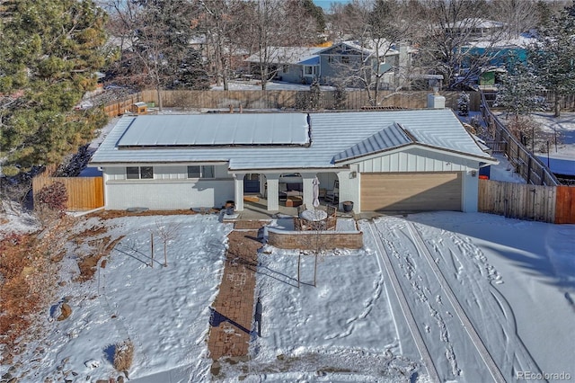 single story home with solar panels, a porch, and a garage