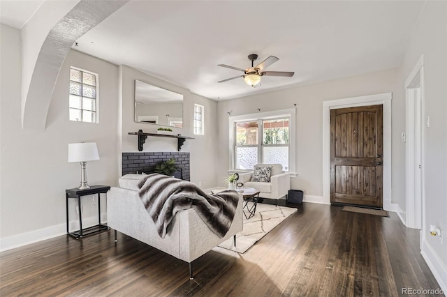 living room featuring dark hardwood / wood-style floors, a fireplace, and ceiling fan