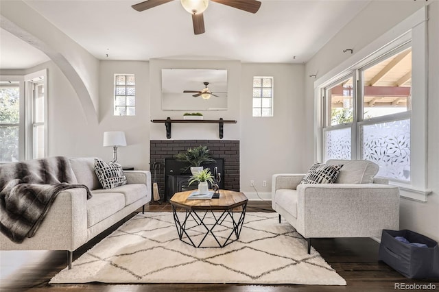 living room with a fireplace, dark wood-type flooring, and plenty of natural light