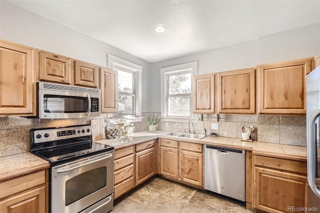 kitchen featuring sink, decorative backsplash, stainless steel appliances, and light brown cabinets