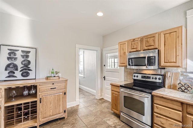 kitchen with tile countertops, tasteful backsplash, and stainless steel appliances