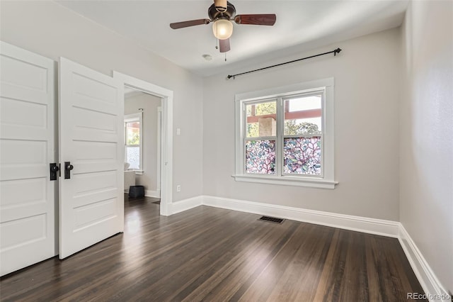 empty room featuring dark hardwood / wood-style floors, plenty of natural light, and ceiling fan