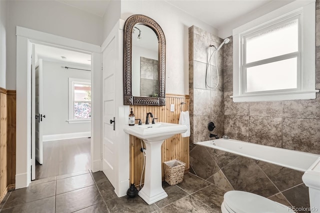 bathroom with toilet, tile patterned flooring, and tiled shower / bath