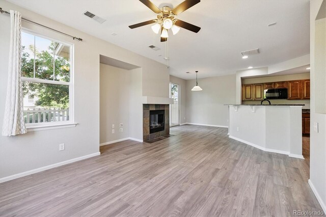 10480 Truckee St Unit B, Commerce City, CO 80022 - unfurnished living room with healthy amount of natural light, light wood-style flooring, ceiling fan, and a tiled fireplace