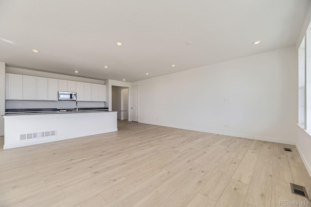 unfurnished living room with visible vents, recessed lighting, baseboards, and light wood-style floors