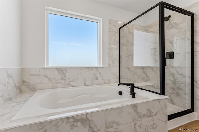 bathroom featuring a garden tub and a marble finish shower