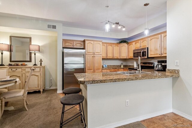 kitchen featuring a breakfast bar, stainless steel appliances, a peninsula, visible vents, and pendant lighting
