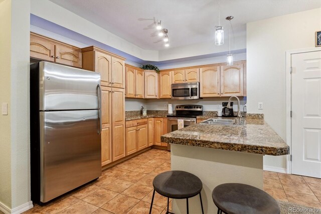 kitchen featuring a kitchen breakfast bar, a sink, light tile patterned floors, a peninsula, and stainless steel appliances