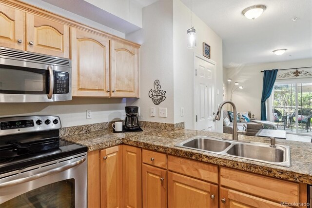 kitchen with light brown cabinets, tile counters, a sink, appliances with stainless steel finishes, and hanging light fixtures