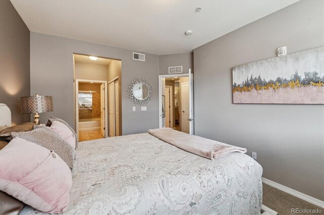 bedroom with visible vents, carpet, baseboards, and ensuite bath