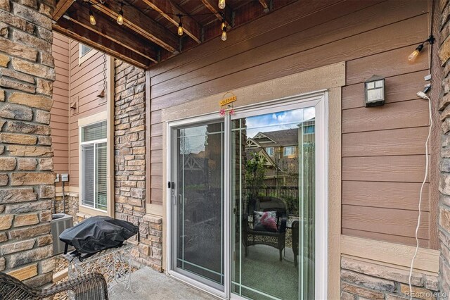 view of exterior entry featuring central AC unit and stone siding
