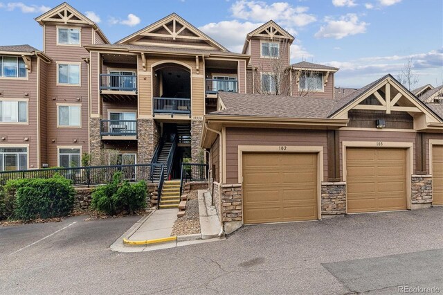townhome / multi-family property featuring a shingled roof and stone siding