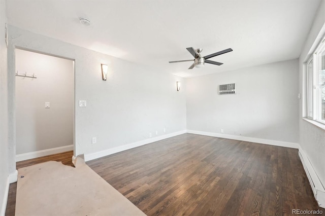 empty room with ceiling fan, a baseboard heating unit, and dark hardwood / wood-style flooring