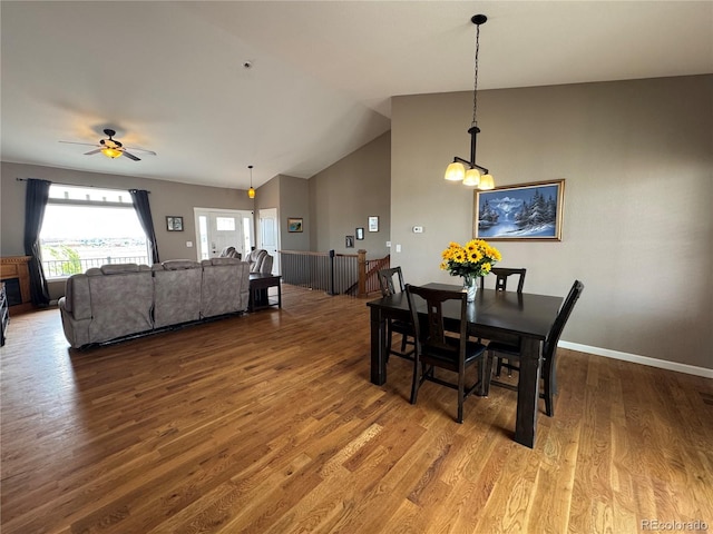 dining room with a ceiling fan, lofted ceiling, baseboards, and wood finished floors