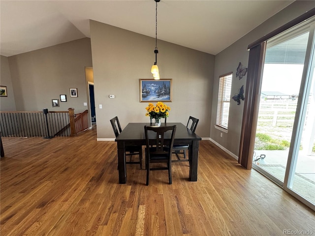 dining room featuring baseboards, wood finished floors, and lofted ceiling