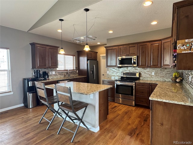 kitchen featuring light stone countertops, stainless steel appliances, tasteful backsplash, and dark wood-style floors