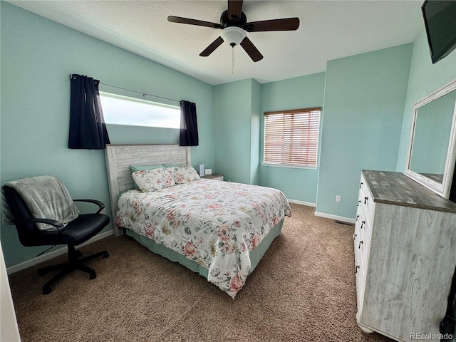 carpeted bedroom featuring multiple windows, baseboards, and a ceiling fan