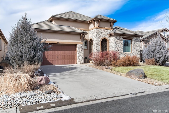 view of front facade with an attached garage, driveway, stone siding, and stucco siding