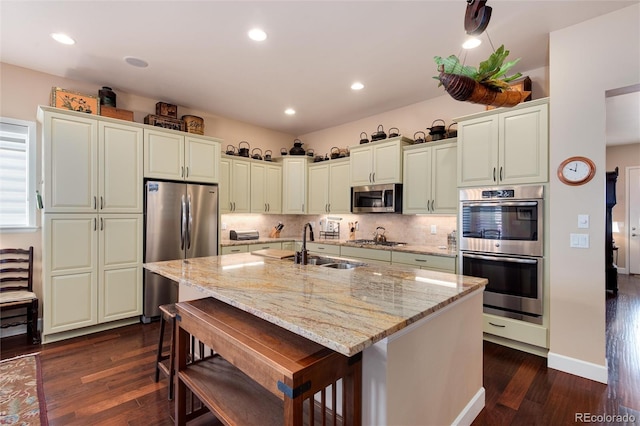 16 Willowcroft Dr, Littleton, CO 80123 - kitchen with stainless steel appliances, dark wood-style flooring, a center island with sink, light stone countertops, and recessed lighting