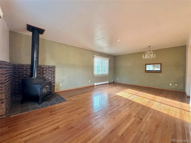 unfurnished living room with a wood stove, wood finished floors, baseboards, and baseboard heating