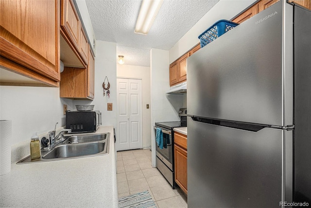 309 E Highline Cir Unit 102, Centennial, CO 80122 - kitchen with stainless steel appliances, under cabinet range hood, brown cabinetry, a textured ceiling, and light tile patterned floors
