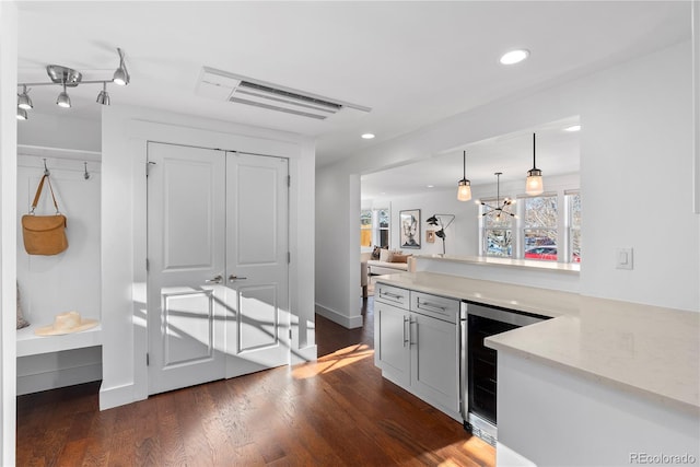 kitchen featuring beverage cooler, hanging light fixtures, light stone counters, dark hardwood / wood-style flooring, and kitchen peninsula