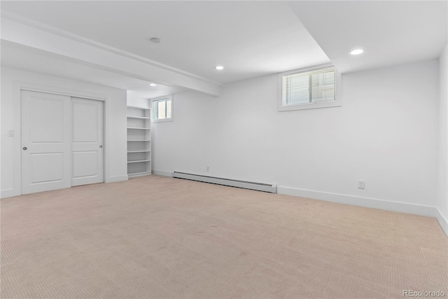 basement with plenty of natural light, light colored carpet, and a baseboard radiator