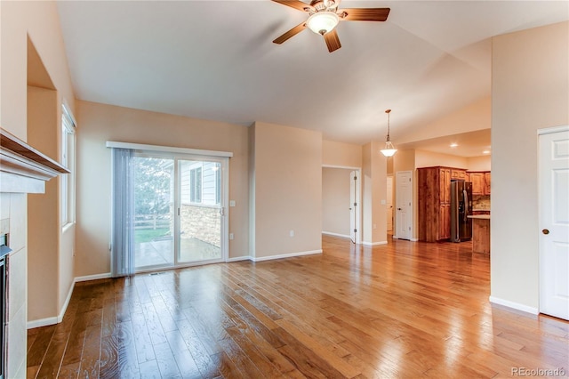 107 Carina Cir, Loveland, CO 80537 - unfurnished living room featuring ceiling fan, light wood-type flooring, vaulted ceiling, baseboards, and a tile fireplace