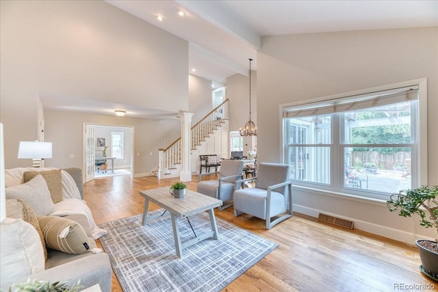 8167 S Wabash Ct, Centennial, CO 80112 - living room with high vaulted ceiling, stairway, light wood finished floors, and a chandelier