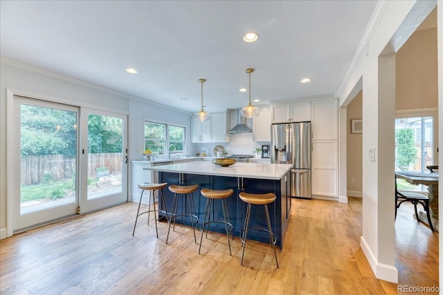 8167 S Wabash Ct, Centennial, CO 80112 - kitchen featuring stainless steel fridge with ice dispenser, wall chimney range hood, crown molding, light countertops, and white cabinets