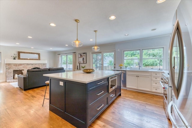 8167 S Wabash Ct, Centennial, CO 80112 - kitchen featuring freestanding refrigerator, white cabinets, light countertops, light wood finished floors, and recessed lighting