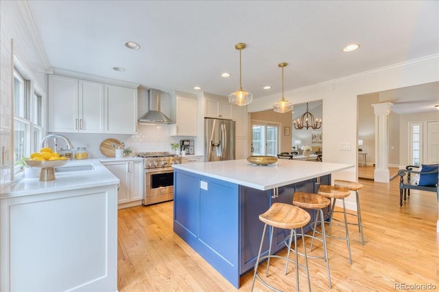 8167 S Wabash Ct, Centennial, CO 80112 - kitchen featuring stainless steel appliances, wall chimney range hood, white cabinetry, a kitchen island, and light countertops
