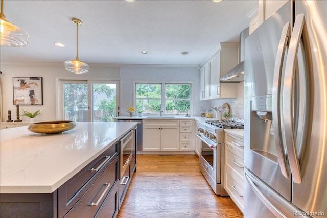 8167 S Wabash Ct, Centennial, CO 80112 - kitchen with appliances with stainless steel finishes, white cabinetry, light wood-style flooring, ornamental molding, and hanging light fixtures