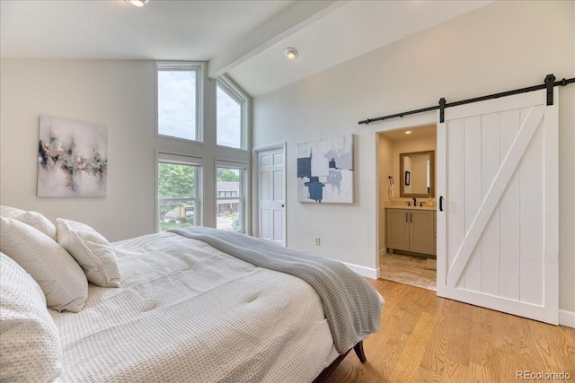 8167 S Wabash Ct, Centennial, CO 80112 - bedroom featuring a barn door, light wood finished floors, beam ceiling, high vaulted ceiling, and ensuite bath
